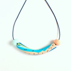 a necklace made out of polymer beads and wood on a blue cord with an orange bead