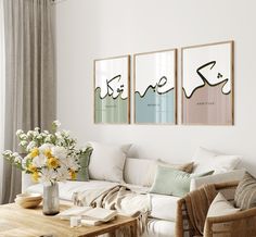 a living room filled with furniture and flowers on top of a wooden table in front of two paintings