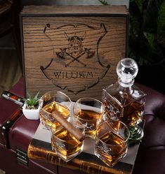 three glasses of whiskey sitting on top of a wooden box next to an empty bottle