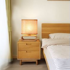 a nightstand with a lamp on it next to a bed