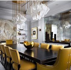 a dining room table with yellow chairs and chandelier hanging from it's ceiling