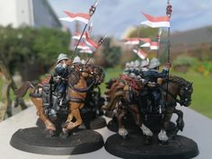 two figurines of men on horses with flags in the backgrouds