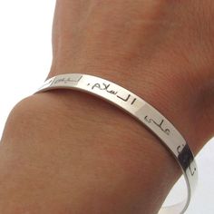 Custom Arabic engraved bangle bracelet for women. Handcrafted in Sterling silver, this distinctive, minimalist style design will spell your message with the engraving of your choice.  The band can be both sides customized with your message. It may turn into a fine Muslim gift when engraved with a message in Arabic language.  But I can make the personalization in any language you wish. You design the main bracelet part - the message that will make it really unique! Features: - Engraving up to 50 characters - Gift for her - Quran Bracelet - Personalized Gift - Arabic jewelry - High quality - Shiny finish - Gift wrapping Details: 925 Sterling Silver  Just write me any words, names or dates you want to get engraved! Size: Adjustable  Width 1/5 inch (6mm)  Circumference 6.2 inch  (Europe Size - Minimalist Engraved Name Bangle Bracelet, Minimalist Engraved Bracelet For Promise, Minimalist Engraved Promise Bracelet, Everyday Engraved Bangle Cuff Bracelet, Silver Engraved Bangle Name Bracelet, Minimalist Adjustable Engraved Bangle, Adjustable Minimalist Engraved Bangle, Engraved Sterling Silver Name Bangle, Engraved Sterling Silver Bangle Name Bracelet