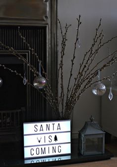 a lighted sign sitting on top of a table next to a vase filled with branches