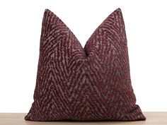 a red and grey pillow sitting on top of a wooden table