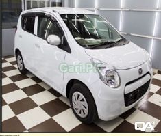 a small white car is parked in a room with black and white checkered flooring