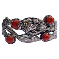 This is a wonderful antique Chinese Dragon Bracelet in Sterling Silver and adorned with beautiful Coral cabochons. The silver work is extraordinary with a fantastic Dragon motif that extends throughout the bracelet. The bracelet is accented by four Coral cabochons. The dragon has fabulous high relief details that create great dramatic effect. The bracelet opens to fit over the wrist and has a screw type closure. The interior of the bracelet is 7 inches (18 cm) around. The top of the bracelet is Antique Silver Cabochon Bracelets, Dragon Chino, Dragon Motif, Dragon Bracelet, Dragon Jewelry, Silver Dragon, High Relief, Silver Work, Chinese Dragon