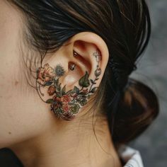 a woman with tattoos on her ear and behind the ear is a flower tattoo design