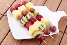 fruit skewers are arranged on a white plate