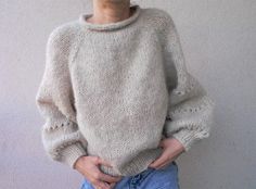 a woman standing in front of a white wall with her hands on her hips wearing a sweater