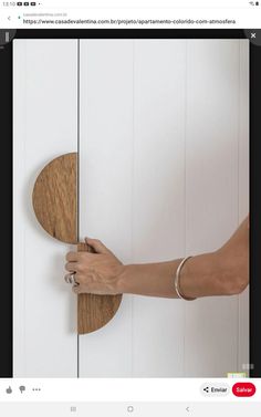 someone is holding the door handle on a white cabinet with wood grained panels and handles