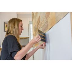 a woman is working on a wood paneling project