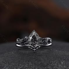 a white gold ring with an intricate design on the side and a black diamond in the middle