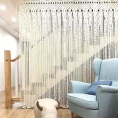 a blue chair sitting in front of a window next to a stair case with beads on it