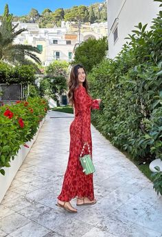 a woman in a red dress is walking down the street with her hand on her hip