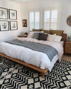 a bed room with a neatly made bed and pictures hanging on the wall above it