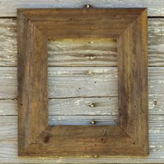 a wooden frame hanging on the side of a wood wall with nails sticking out of it