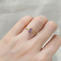 a woman's hand wearing a gold ring with an amethoraite and diamond