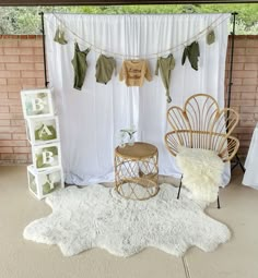 two chairs and a table in front of a white backdrop with clothes hanging on it