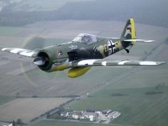 an airplane is flying in the sky over farmlands and fields with houses on either side