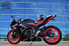 a red and black motorcycle parked in front of a building with blue skies behind it