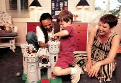 two adults and a child are playing with toys in a room that looks like a castle