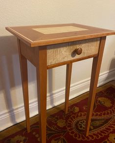 a small wooden table sitting on top of a carpeted floor next to a wall