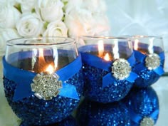 three blue glittered wine glasses with candles in them