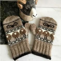 two knit mittens sitting on top of a marble counter next to a stuffed animal