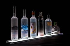 a row of bottles sitting on top of a shelf next to each other in front of a black background