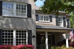 a large gray house with black shutters and flowers