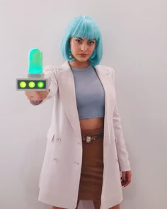 a woman with blue hair is holding a green light up device in her right hand