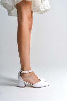 a woman's legs wearing white shoes and a dress with pearls on the bottom