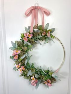 a wreath with pink flowers and green leaves