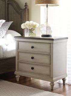 a white nightstand with flowers on top of it