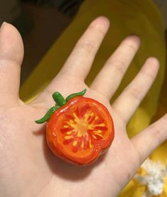 a tiny tomato sitting on top of someone's hand