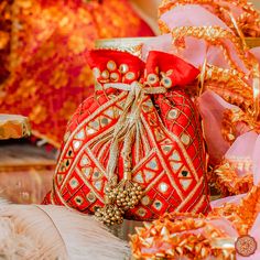 a red bag with gold decorations on the front and sides, sitting next to some feathers