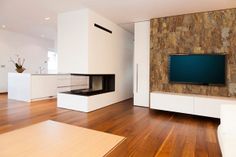 a living room with wood flooring and white furniture in front of a flat screen tv mounted on a wall