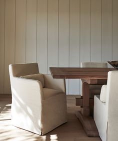 two chairs and a table in a room with wood paneling on the wall behind them