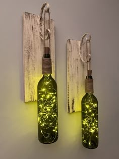 two bottles with lights attached to them are hanging on the wall next to each other