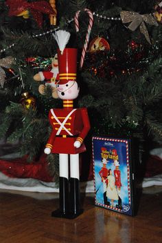 a nutcracker is standing next to a christmas tree with a dvd on it