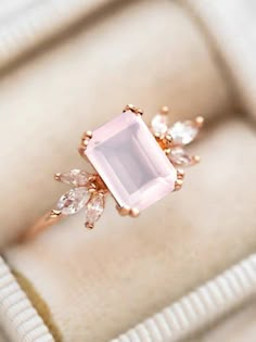 an engagement ring with a pink stone surrounded by white and clear stones in a box