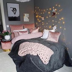 a bedroom decorated in pink and grey with lights