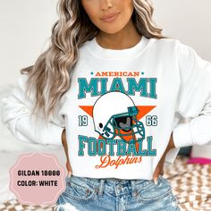 Show your team pride with this amazing Vintage Star Miami Dolphins Football Crewneck! Perfect for cooler days and game nights, this crewneck sweatshirt combines classic style and comfort, making it a must-have for any Dolphins fan. Available in a range of sizes, this crewneck offers a great fit for fans of all ages. Its versatile design makes it perfect for layering over your favorite game day outfit or wearing casually. Treat yourself or surprise a fellow Dolphins fan with this essential additi Football Outfits For Women, Cute Dolphins, Miami Vintage, Football Crewneck, Miami Dolphins Logo, Miami Dolphins Football, Dolphins Logo, Dolphins Football, Vintage Miami