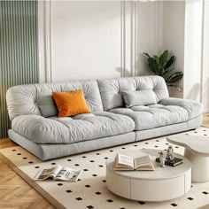 a living room with a white couch and coffee table on top of a rug in front of a window