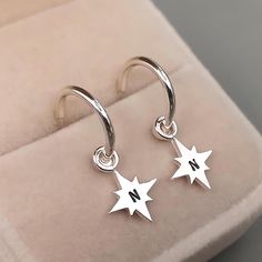 Introducing our exquisite Initial North Star Hoop Earrings, meticulously handcrafted with sterling silver. The North Star, a symbol of guidance and inspiration, shines brightly on these hoop earrings, making them a meaningful and enchanting accessory. Each earring is carefully handmade with attention to detail, ensuring a high-quality piece that you'll cherish for years to come. These earrings offer versatility and customization, as the North Star charm can be easily removed and interchanged wit Silver Engraved Hoop Earrings For Gift, Silver Sterling Silver Huggie Earrings For Gift, Silver Dangle Hoop Earrings With Star Charm, Silver Jewelry With Star Charm For Anniversary, Silver Sterling Silver Earrings With Star Charm, Silver Star Charm Jewelry For Anniversary, Silver Small Hoop Jewelry With Star Charm, Sterling Silver Hallmarked Huggie Earrings For Gifts, Gift Hallmarked Sterling Silver Huggie Earrings