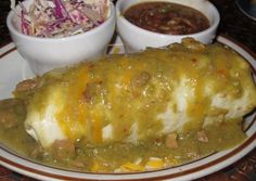 a plate topped with enchiladas and salsa next to bowls of coleslaw