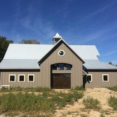 a large gray barn sitting on top of a dirt field