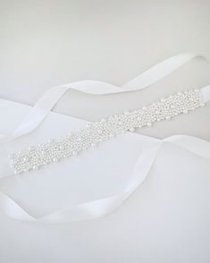 "A statement sash is encrusted with beautiful pearls attached on bridal white double-faced satin ribbon. This classic pearly belts creates a romantic finishing touch to your bridal gown, bridesmaids and flower girls, or as hair accessories.  DETAIL: Adult Size 108\" Kids Size 78\" Headband Size 60\" Applique size: 12\" length, 2\" wide/1.25\" wide - We DO NOT offer refunds.  Selected items are eligible for EXCHANGE ONLY within 14 days of delivery date.   All accessories are FINAL SALE. - We are White Adjustable Bridal Accessories For Bridesmaids, Beaded White Bridal Belt For Party, Elegant Bridal Belt With Satin Bow For Bridesmaid, Elegant Bridal Belt With Satin Bow For Wedding, Adjustable White Bridal Belt For Bridesmaid, White Beaded Bridal Belt For Party, Adjustable Bridesmaid Bridal Belt With Sashes, Adjustable Ribbon Wedding Sashes, Adjustable Bridal Belt With Sashes For Bridesmaid