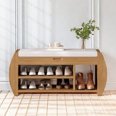 a wooden shoe rack filled with shoes next to a white wall and potted plant